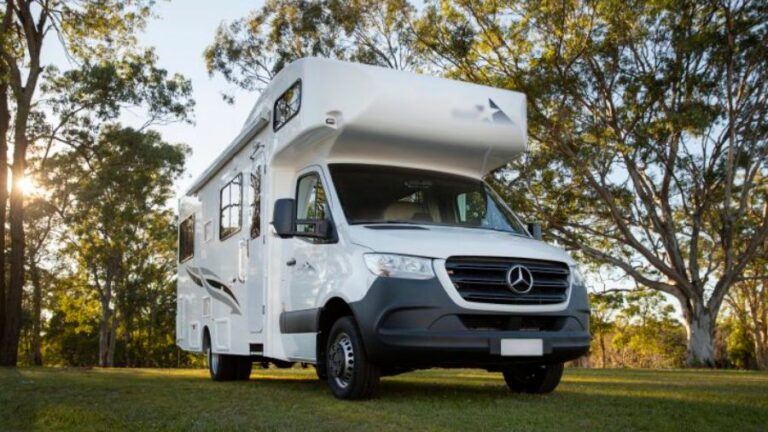 Motorhome branco estacionado em área arborizada durante o dia, usado como imagem destacada do artigo