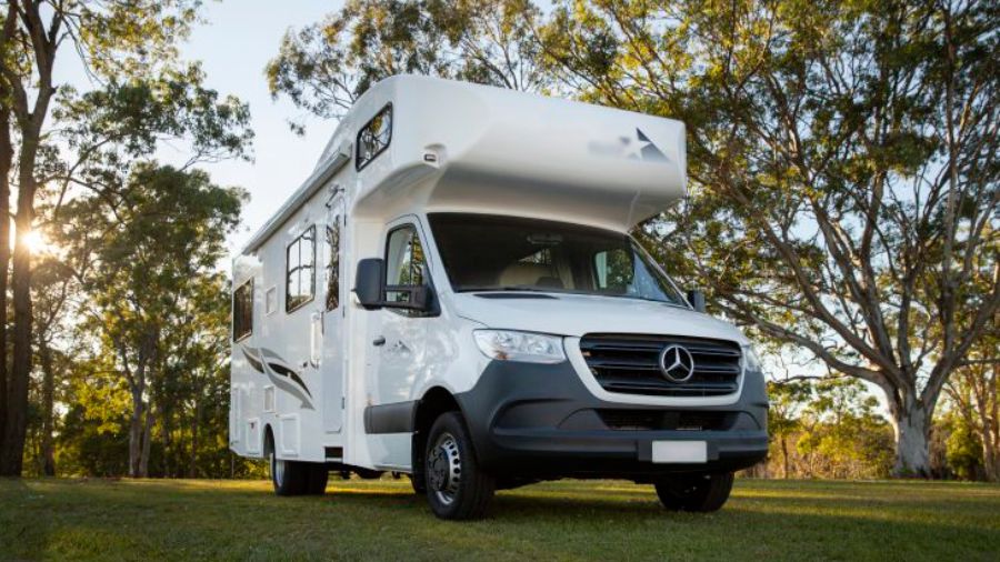 Motorhome branco estacionado em área arborizada durante o dia, usado como imagem destacada do artigo