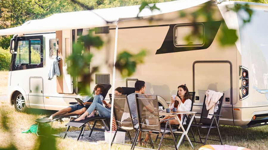 Família reunida ao lado de motorhome estacionado em camping no Brasil, aproveitando área ao ar livre