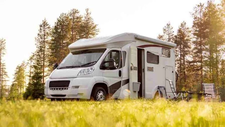 Motorhome estacionado em área de camping cercada por árvores, usada como imagem destacada do artigo